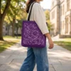 Product photoshoot of artistic Arabic calligraphy Cosmic tone tote bag held shoulder down by a model at a university campus - tote size 18"X18" - binmahmood