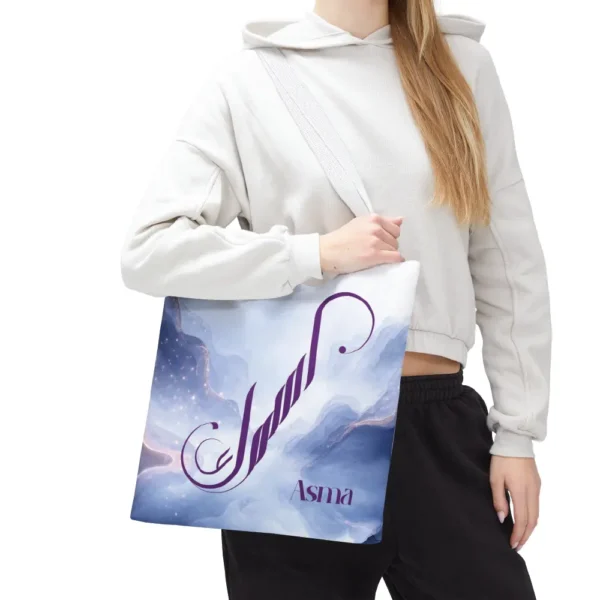 Asma name in BinMahmood original Arabic fusion calligraphy in plum purple ink on a white polyester tote bag with white handles, marble cloud background — mouse-crafted by BinMahmood