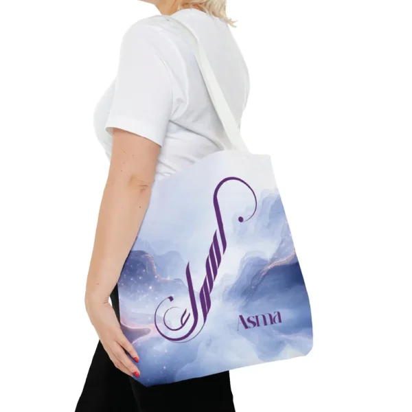 Asma name in BinMahmood original Arabic fusion calligraphy in plum purple ink on a white polyester tote bag with white handles, marble cloud background — mouse-crafted by BinMahmood