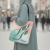 Custom Maryam tote bag featuring transformative teal Arabic calligraphy on a soft peach and teal watercolor background by BinMahmood.