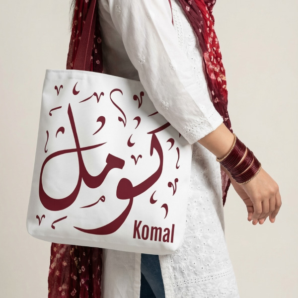 Personalized optic white tote bag with Komal Arabic Diwani calligraphy in maroon script with deep maroon handles, 200gsm polyester construction. BinMahmood Bedouin Love series, working women edition