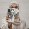 Uzma name in BinMahmood original Arabic fusion calligraphy in grey on a dual-layer protective phone case, styled against an edgy halftone art backdrop — mouse-crafted by BinMahmood