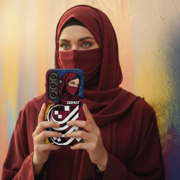 modest female with hijab and niqab holding Samsung S25 with a visible Zeenat name Arabic Typography by binmahmood on the mobile phone cover