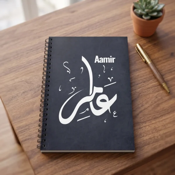 Product photoshoot of Aamir personalized Arabic Diwani calligraphy spiral notebook place on a wooden table with a pen and a small flower pot - binmahmood