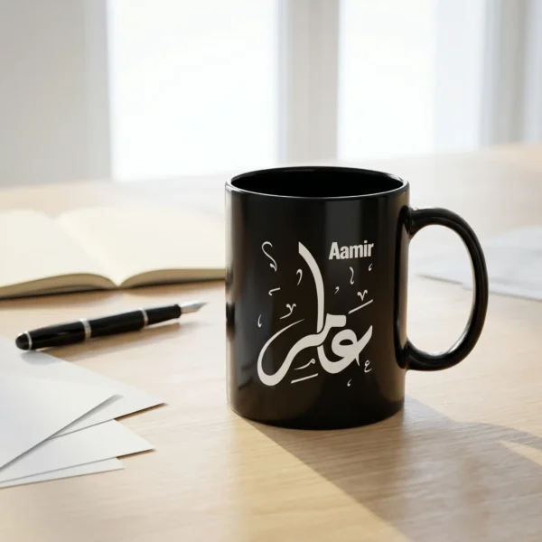 Product Photography of Aamir Arabic name mug in black ceramic with white Diwani calligraphy, personalized Islamic gift for him on a white table with an open notebook, a fountain pen and some scattered papers in the background