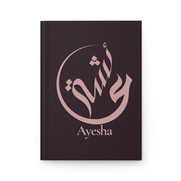 Ayesha name journal cover in plum with muted rose gold Arabic calligraphy, product mockup on white background