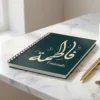 Product photo of Fatimah Arabic name calligraphy notebook lay flat on a white marble top with pen with a gold colour pen - binmahmood