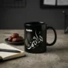 Product photoshoot of Hashim personalized Arabic name calligraphy black mug placed on a weathered concrete surface surrounded by an open notebook, a pen and a plate filled with dates fruit - binmahmood