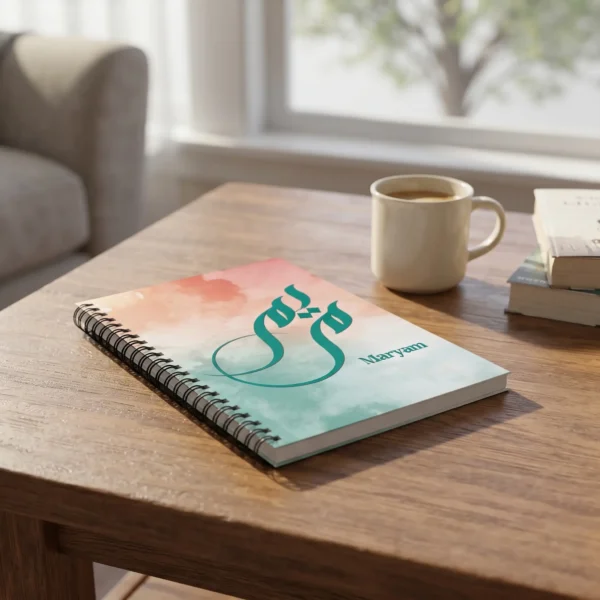 Product photography of Maryam Arabic Sunbuli fusion calligraphy name art spiral notebook, lay flat on coffee table - binmahmood