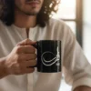 Close-up of a model holding a black ceramic mug with the name Faraz rendered in white Sunbuli-style Arabic calligraphy. The script features a dramatic, modern curve with high-contrast digital precision.
