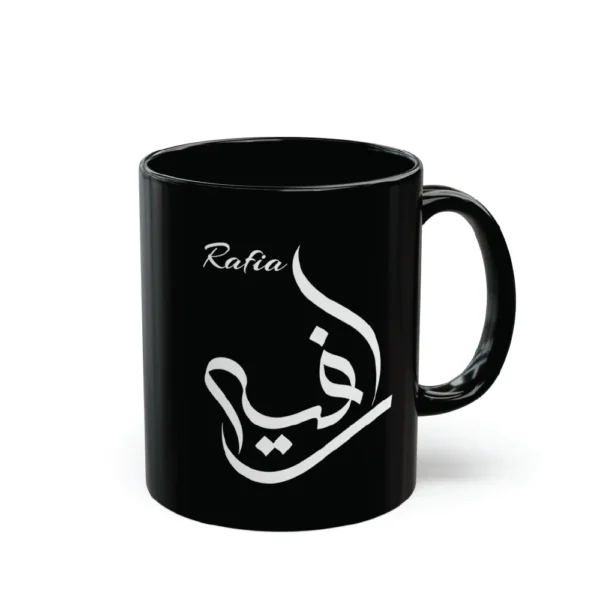 A model in a cream-colored outfit holding a glossy black ceramic mug featuring the name Rafia in white Al Wissam Arabic calligraphy. The design is precision mouse-crafted and displayed in a minimalist lifestyle setting.