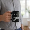 Product photoshoot of Sami personalized fusion Arabic calligraphy black mug with white printing, held by a model at chest height - binmahmood