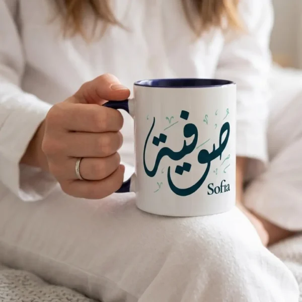 Model photoshoot of Sofia Arabic Calligraphy Mug in Diwani Script with a dark blue handle and inner, held by a model in her hands, the mug sits on the knees of the model