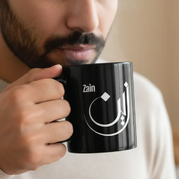 Zain personalized black coffee mug with Arabic calligraphy, styled on a wooden desk