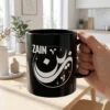 Man holding Zain Arabic name mug in black ceramic with white Diwani calligraphy and nuqta detailing, personalized Islamic gift for him